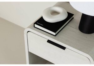 Elegant nightstand with black drawer handle and decorative items on top.