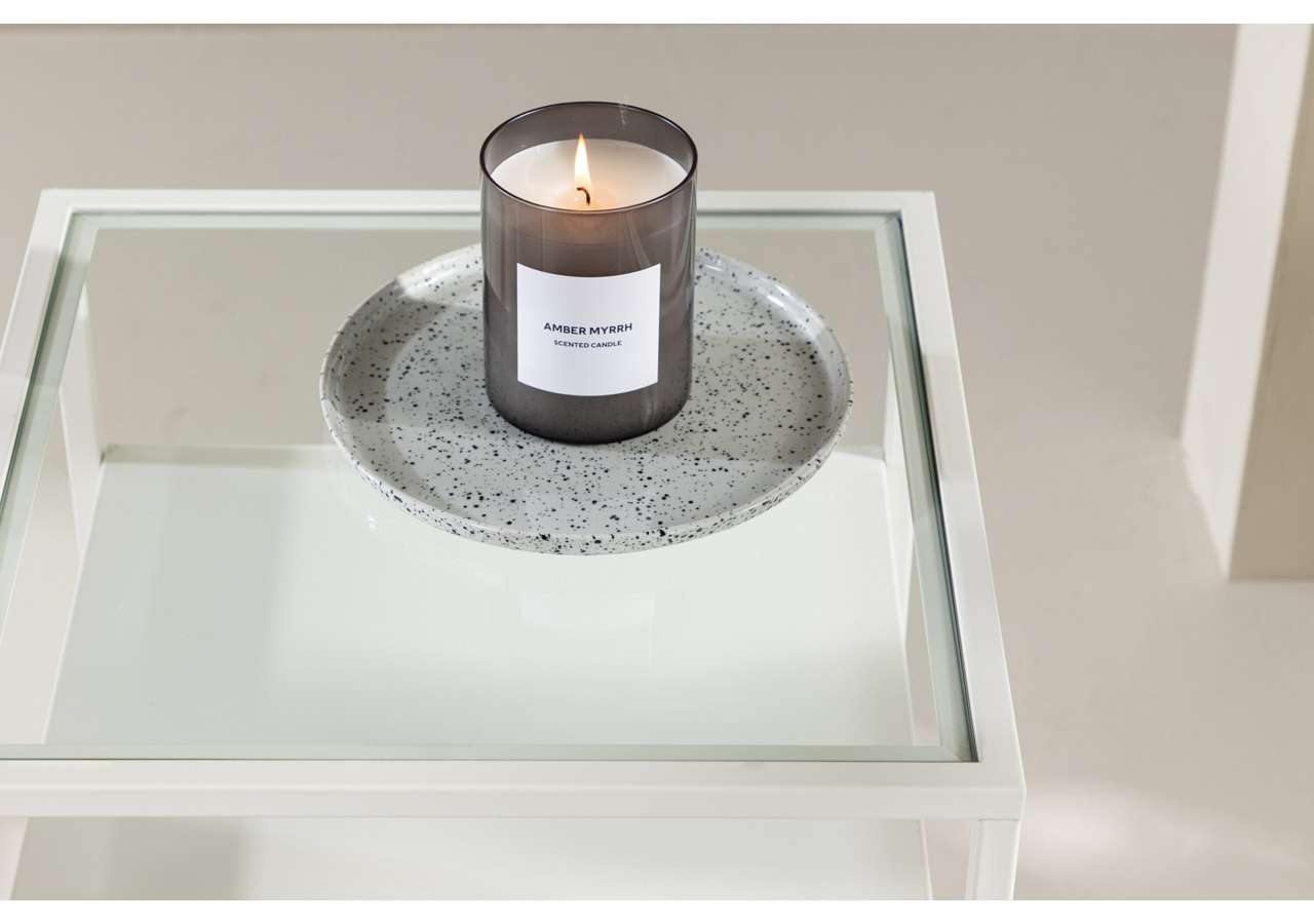 Ljusgrå telyslykta med doftljus på vitt soffbord.