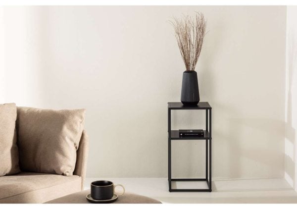 Elegant svart vas med grenar på stilren svart sidebord i vardagsrummet.