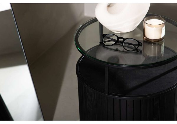 Modern sängfabriken nattbord med svart trädesign, glasplatta och dekorativa tillbehör.