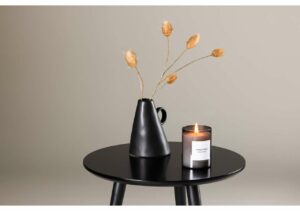 1. Modern svart vas med torkade örter och doftljus på rund svart bord.