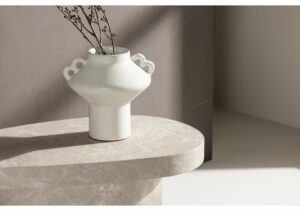 Minimalist vit vas med blomkvistar på marmorbord i ljus stil.