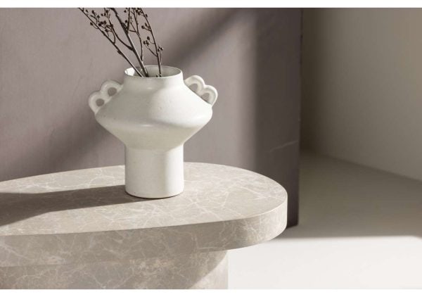 Minimalist vit vas med blomkvistar på marmorbord i ljus stil.