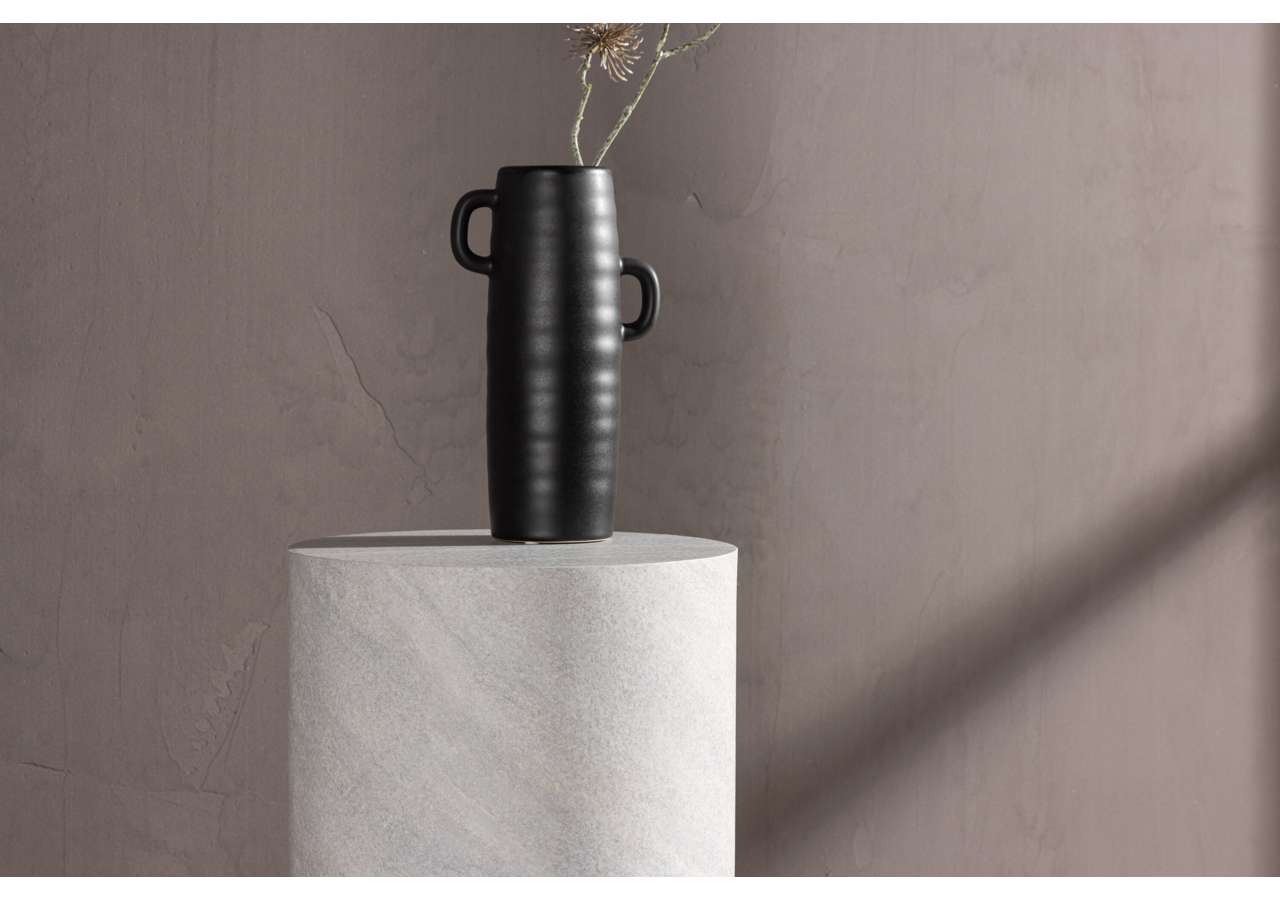 Mörk vas med handtag på marmorpodium, minimalistisk inredning.