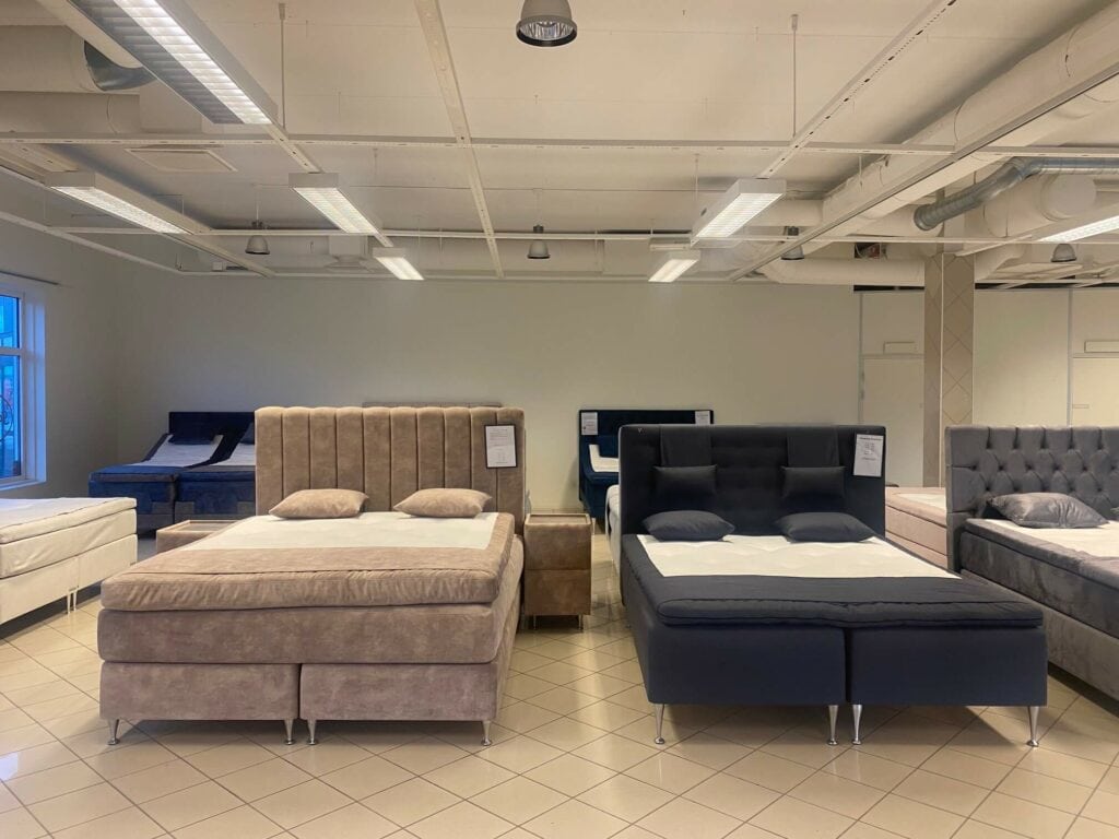 Modern sängar och madrasser i olika stilar och färger i möbelbutik.