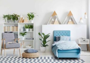 Ljust barnrum med blå säng och moderna hyllor med växter och dekorationer.