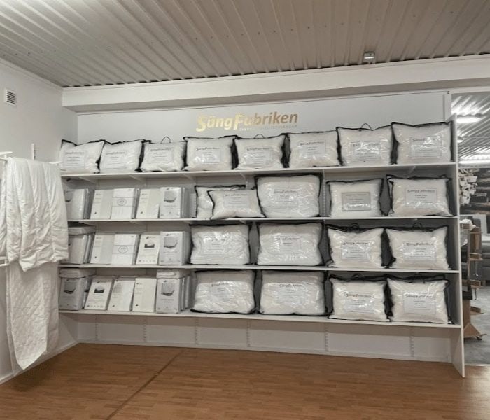 Liggande sängkläder och madrasser från Sängfabriken invid vägg.