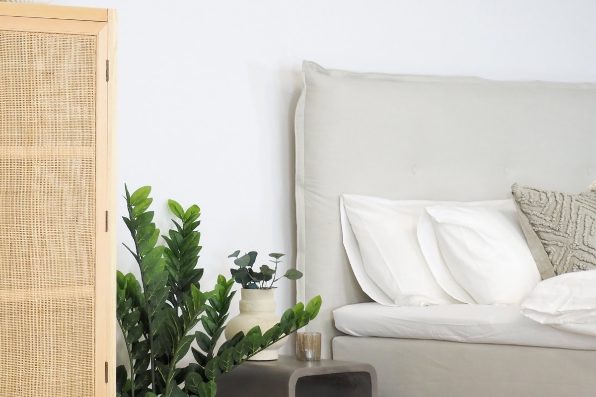 Hållbar sängstomme och nattygsbord med växter i modern sovrumsdesign.