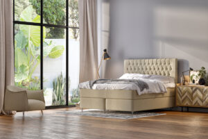 Ljust sovrum med säng, nattduksbord och stor fönsterruta med gröna växter utomhus.