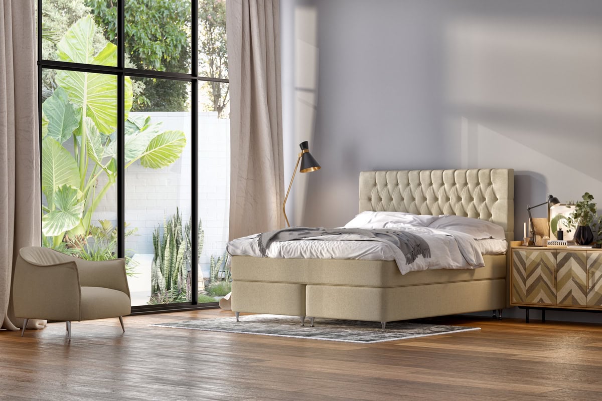 Ljust sovrum med säng, nattduksbord och stor fönsterruta med gröna växter utomhus.