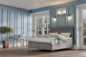 Mörkgrått sängram med kupat huvudgavel i modern sovrumsmiljö.