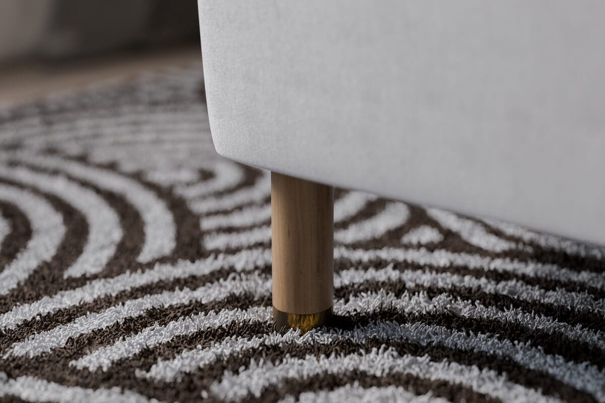 Sängfabriken, modern sängfot med träben på mönstrad matta.