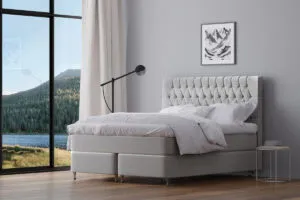 Ljus och modern säng med tuftad områdesgavel i ett elegant sovrum.