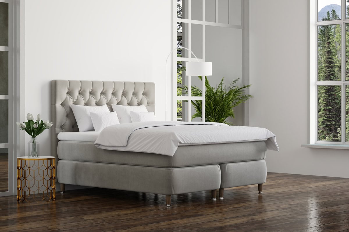 Möblerad sovrum med lyxigt sänggavel och vita sängkläder, stora fönster med utsikt över naturen.