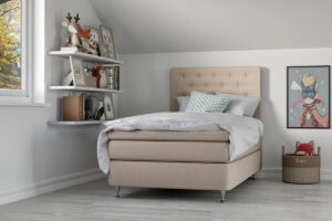 Madrass och sängram i ljus beige för barnrum.