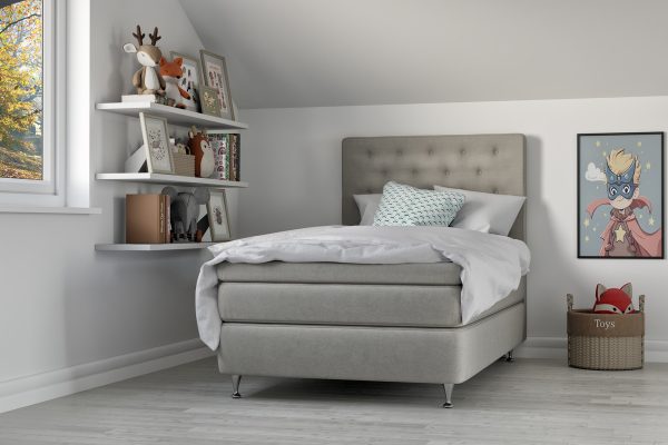 Madrass och sängram i modern sovrumsmiljö med leksaker och barnsäng.