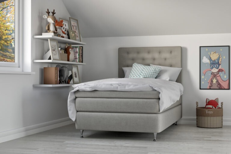 Madrass och sängram i modern sovrumsmiljö med leksaker och barnsäng.