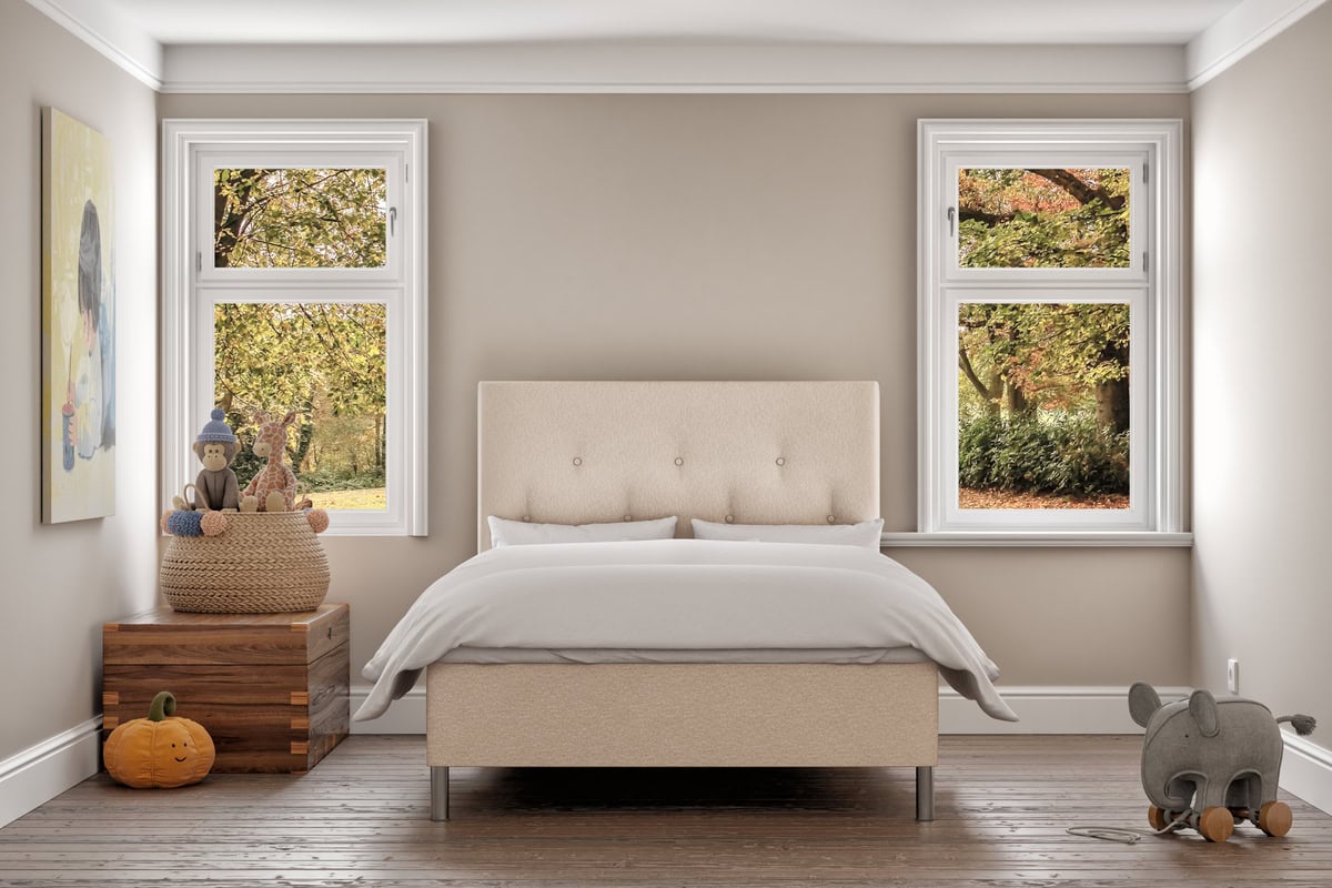 Möblerad sovrum med säng, fönster mot höstlöv, modern design och comfort.