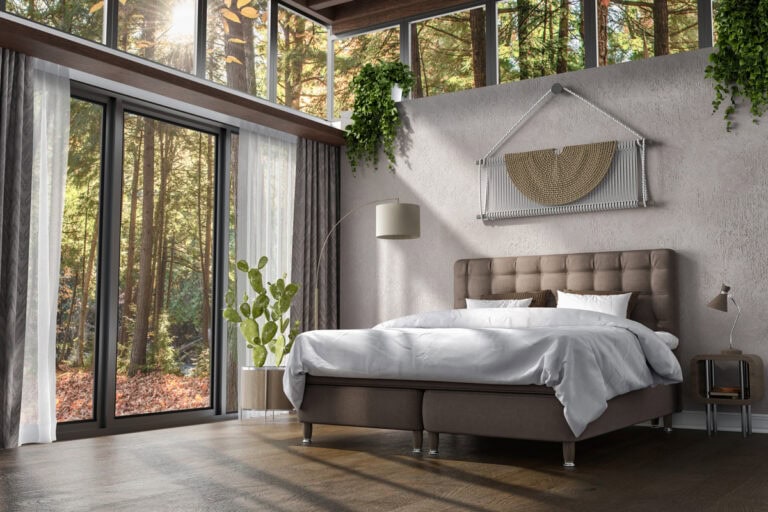 Ljust sovrum med stora fönster mot natur, modern säng och gröna växter, perfekt för avkoppling.