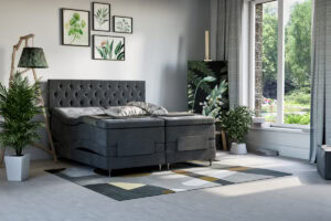 Mörkgrå säng med paneletändstolpe och växter i vitt krukor.