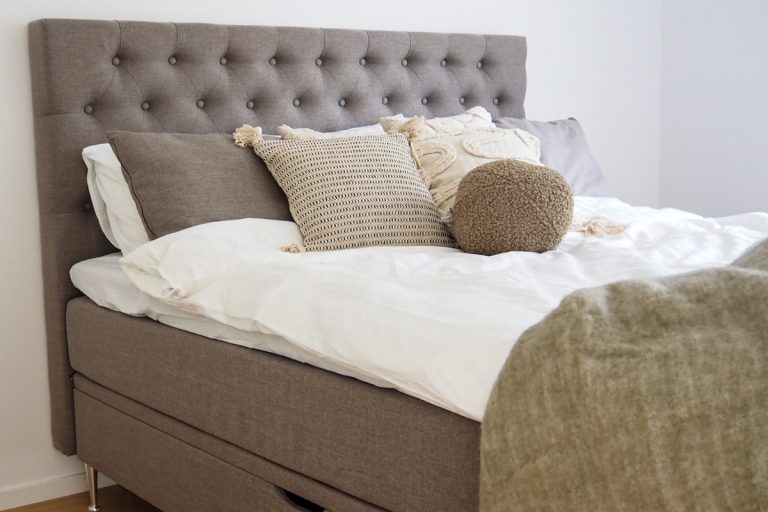 Mordern säng med grått huvudgavel och dekorativa kuddar, perfekt för sovrum inredning.