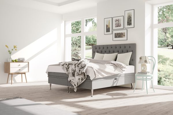 Mjukt sänghuvud och ljusa textilier i ett stilrent sovrum.