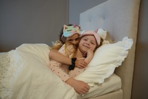 Söt barn i pyjamas med enhörningsmössor i sängen, mysig sovstund.