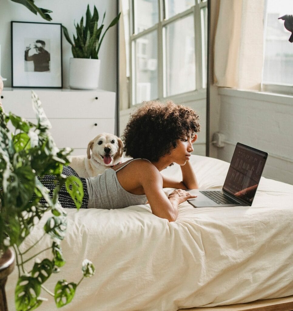 Bekvämt sovrum, kvinna med hund, laptop, inredning, moderna möbler, naturligt ljus, sömn, hemkomfort, avkoppling, inredningsdetaljer.