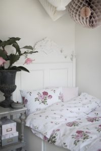 Liggande säng med floral bäddtextil och vintage-inspirerat huvudgavel.