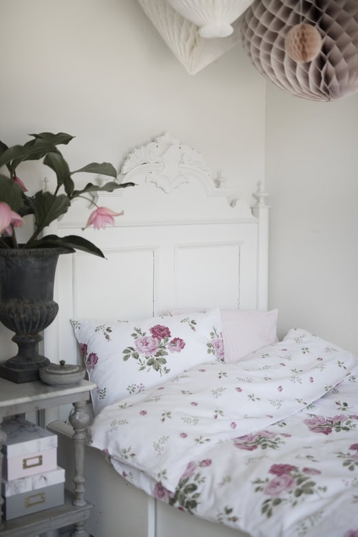 Liggande säng med floral bäddtextil och vintage-inspirerat huvudgavel.