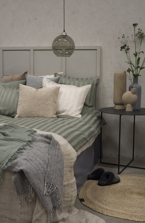 Mysigt sovrum med eleganta sängkläder och dekorativa vaser ihop med mysig belysning.