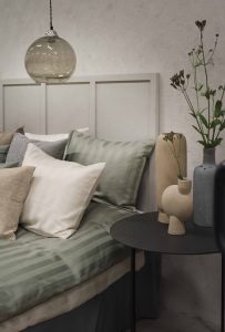 Renforlad mini pendellampa, sängkläder och moderna vaser i sovrum.