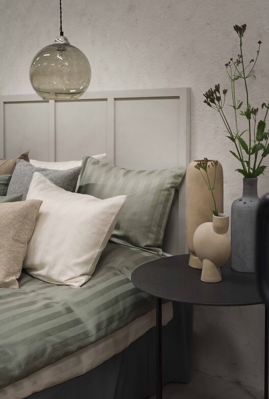 Renforlad mini pendellampa, sängkläder och moderna vaser i sovrum.