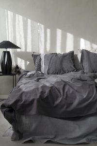 Mörkgrå sängkläder och kuddar i modern sovrumsinredning.