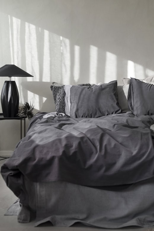 Mörkgrå sängkläder och kuddar i modern sovrumsinredning.