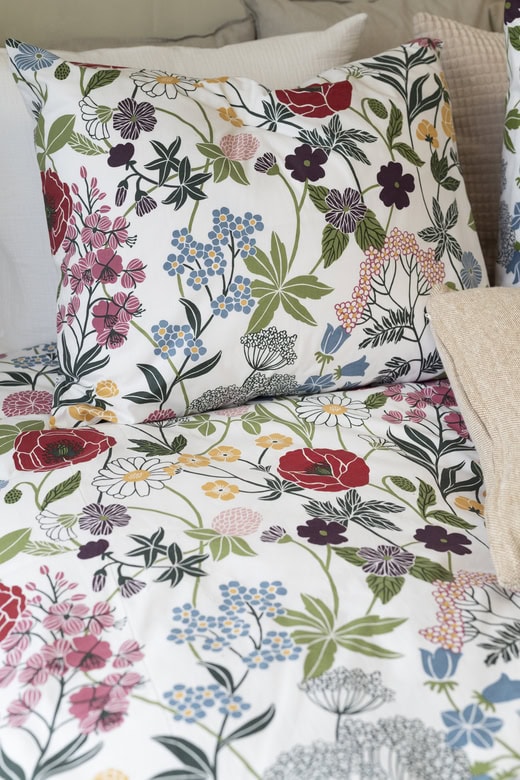 Frotté pillows and bedsheets with colorful floral pattern for bedroom decor.