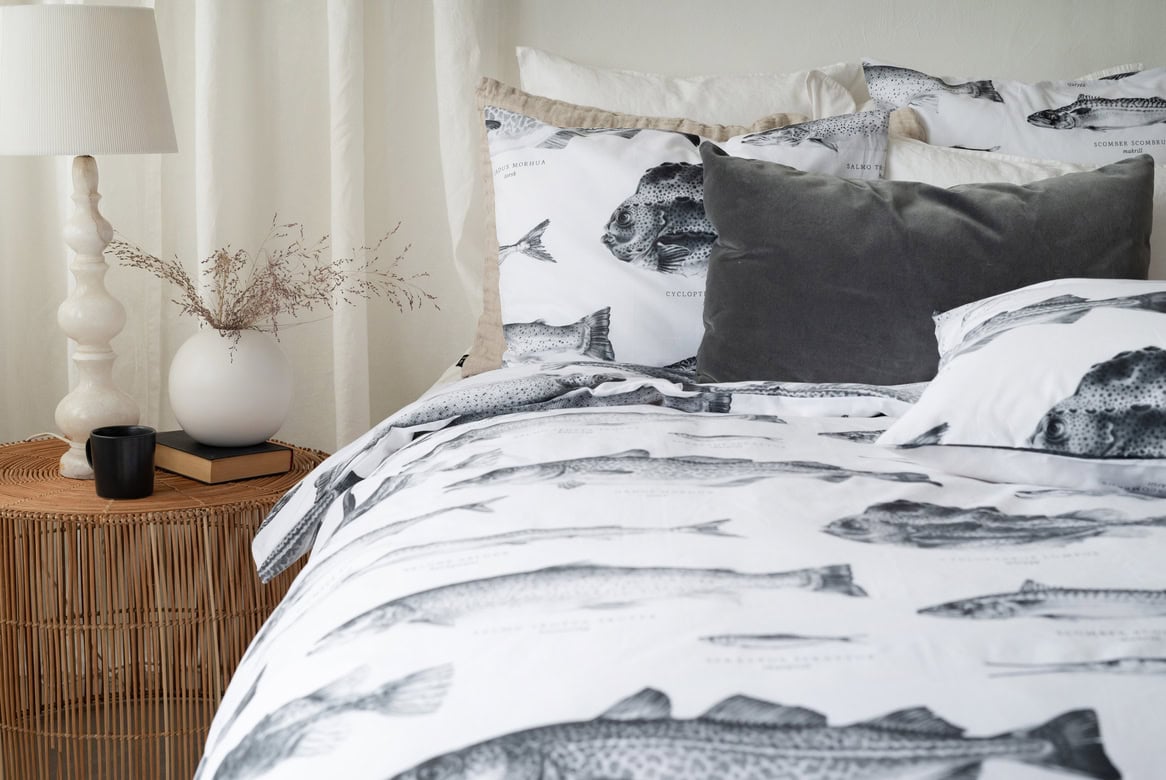 Fiskmönstrat sänglinne i svartvitt med matchande kuddar och mysig sovrumsmiljö.
