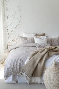 Mjukt sängklädesset i neutrala toner för skönt sovande och elegant sovrumslayout.