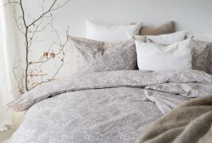 Mjuk säng med linnelakan och kuddar i naturfärger, skapar en lugn sovplats.