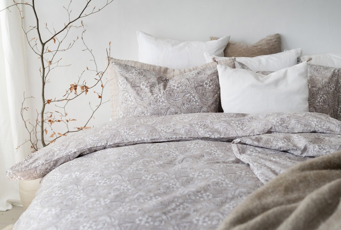 Mjuk säng med linnelakan och kuddar i naturfärger, skapar en lugn sovplats.