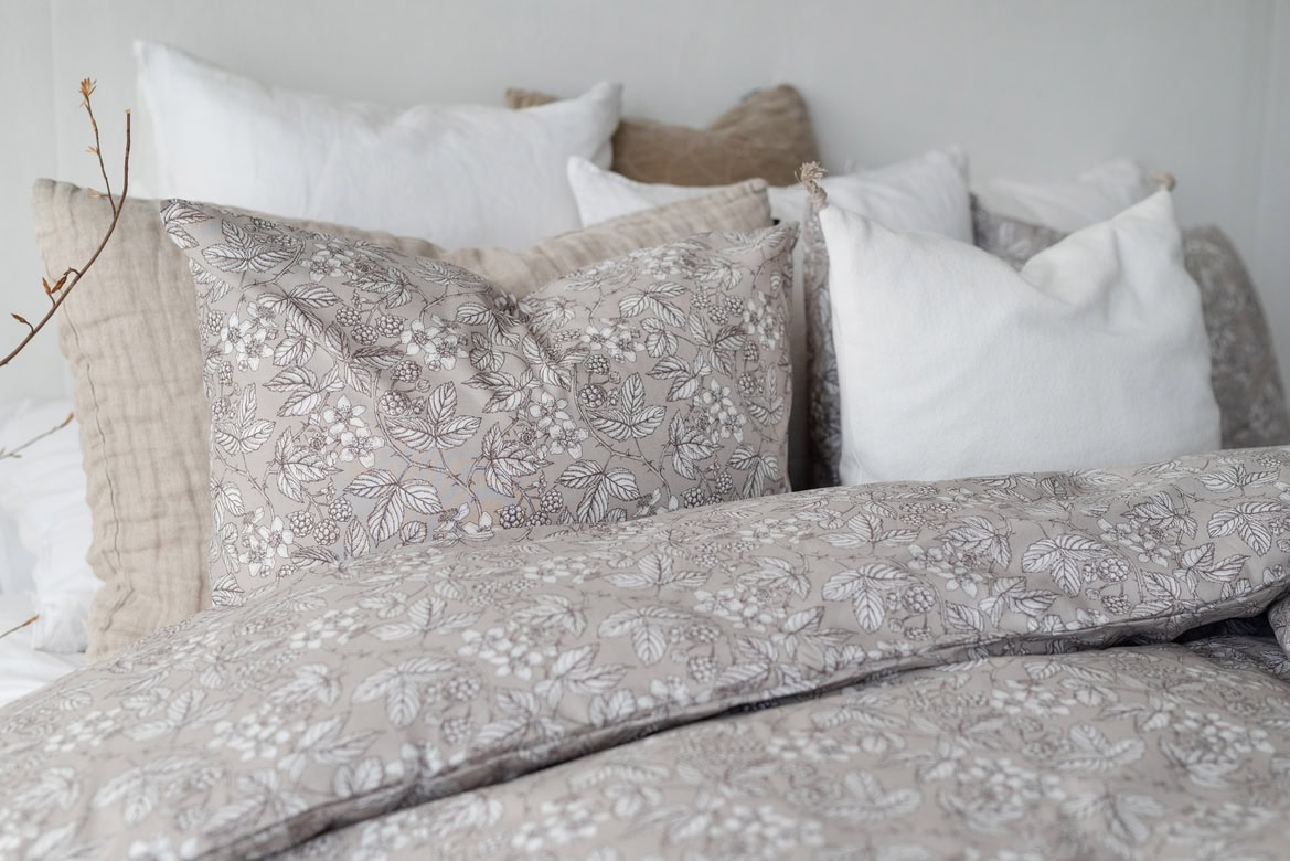 Väldigt fotade sängkuddar med blommönster och naturfärger för ett mysigt sovrum.