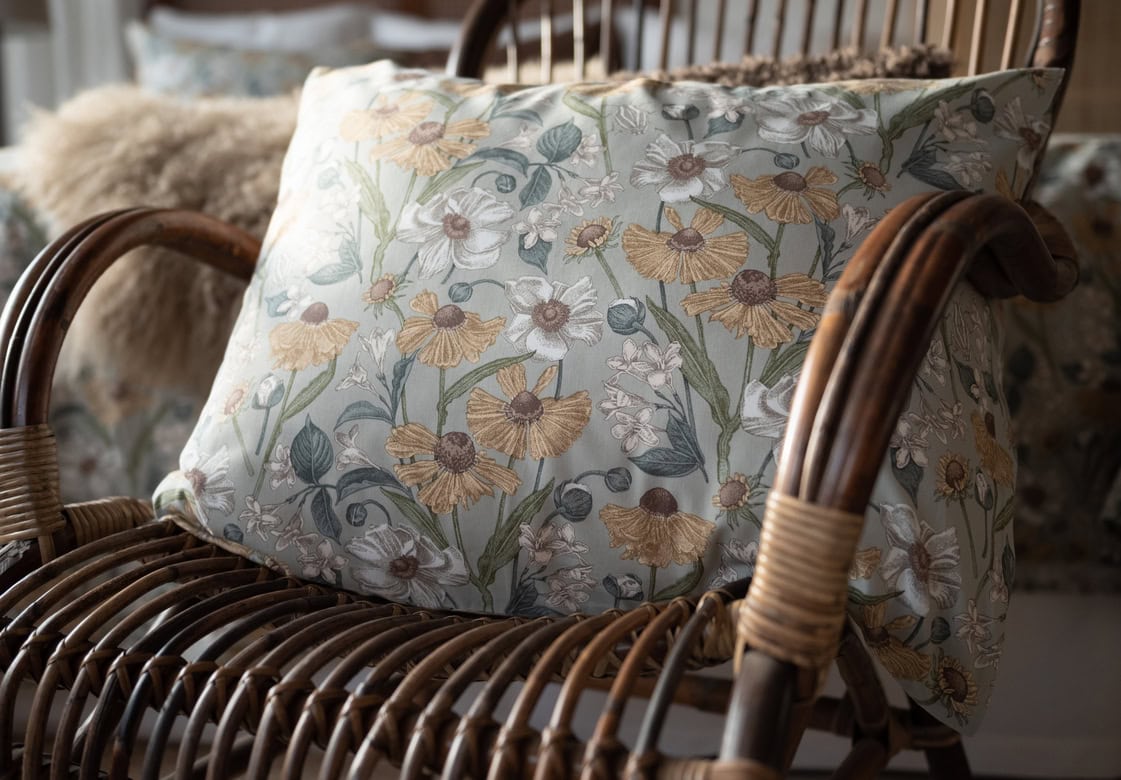 Fåtölj med blomstrande dekorativt kuddfodral i miljö inspirerad av naturen.