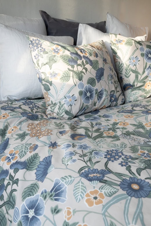 Havsblå och beige blommiga sängkläder i hög kvalitet för en mysig sovrumsmiljö.