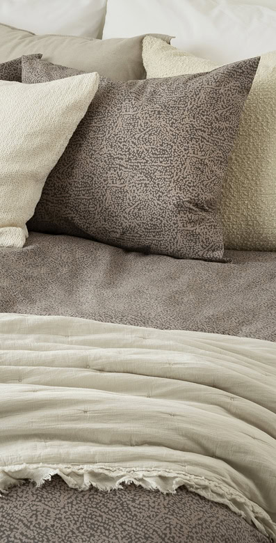 Mjuk och lyxig sängtextil i beige och grå nyanser för en behaglig sömn och elegant sovrumsmiljö.