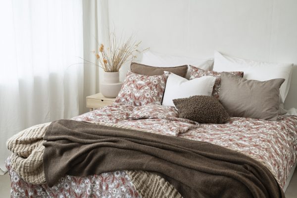 Möblerad säng med sängkläder och kuddar i neutrala färger, skapar en inbjudande sovrumsmiljö.