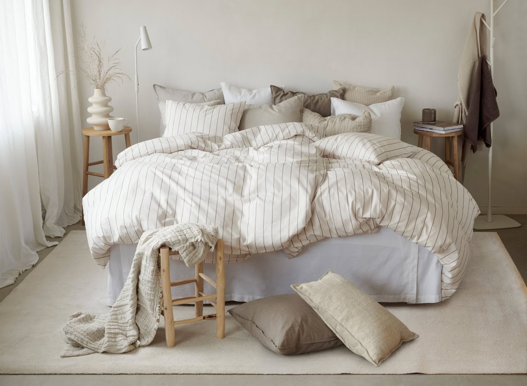 Mjuk och inbjudande sovrum med säng i neutral stil och naturliga textilier.