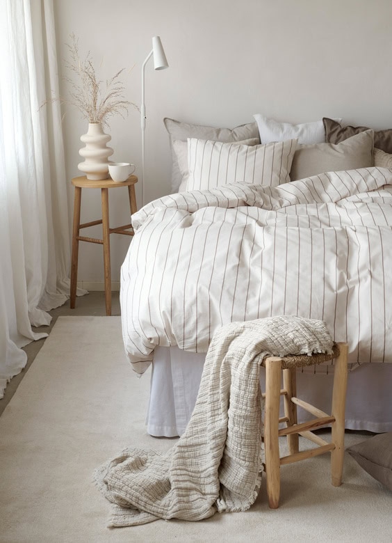 Ljust och elegant sovrum med naturnära sängkläder och minimalistisk inredning.
