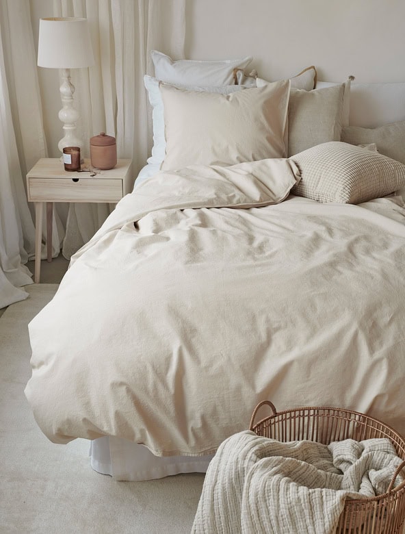 Möbel och sängkläder i naturliga, beige toner för en lugn sovrumsmiljö.