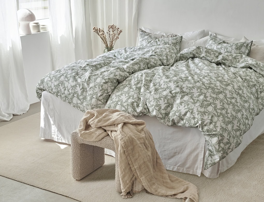 Ljust sovrum med duntäcke och sängkläder med bladmönster, naturlig stil, och mysig atmosfär.
