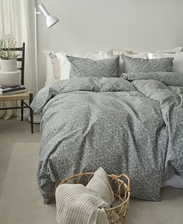 Mjukt överkast och kuddar i sovrum med modern inredning, perfekt för en mysig sovplats.